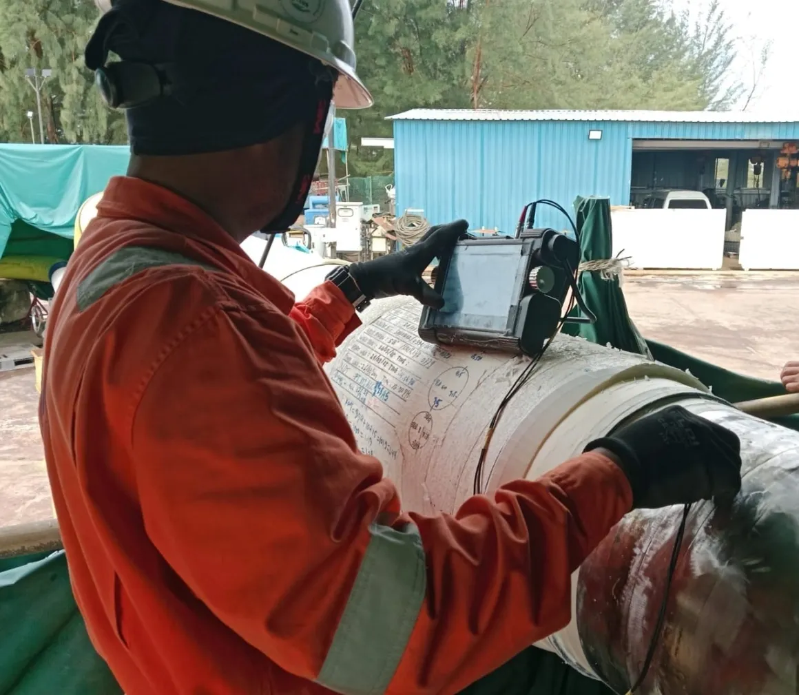 Pioneer Offshore Solutions technician inspecting stainless steel piping with calibrated test equipment
